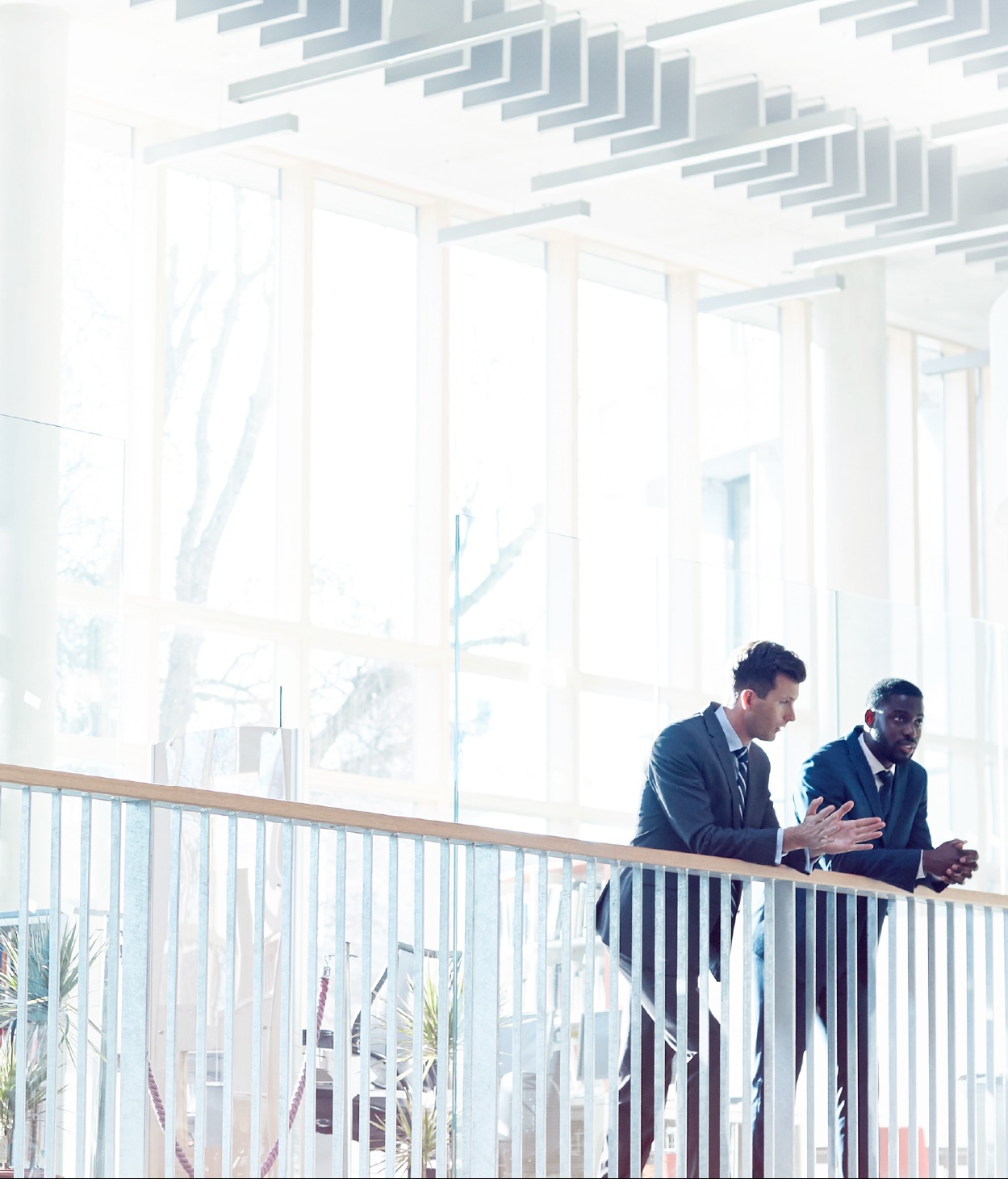 Two businessmen chatting at a balcony railing