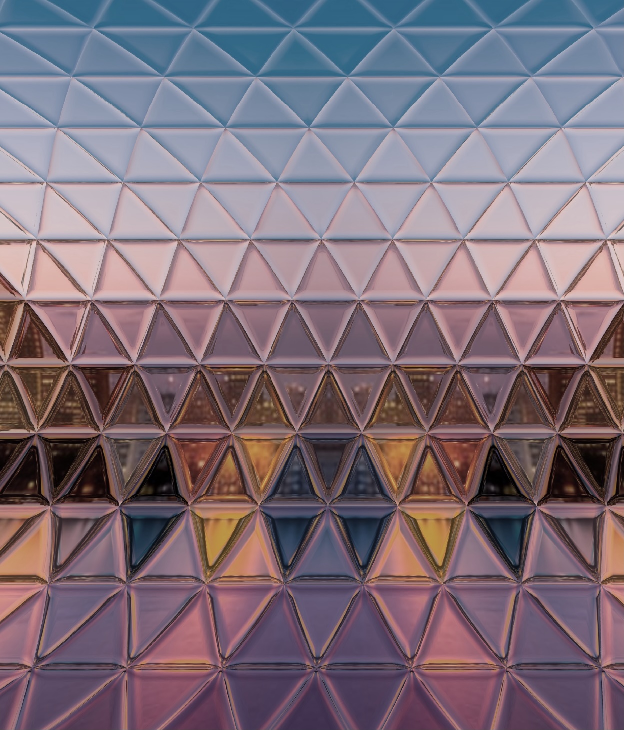 Curved glass building surface with many facets reflecting a city skyline at dusk