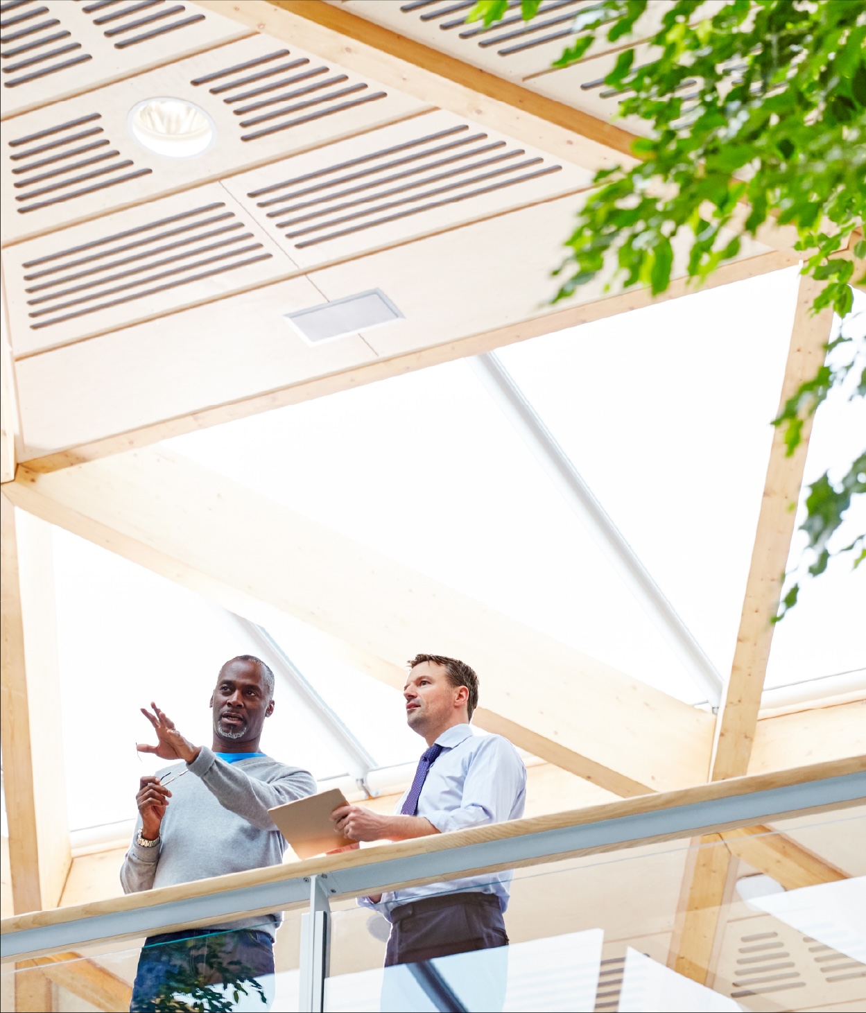 Two businessmen have a discussion on a office balcony.