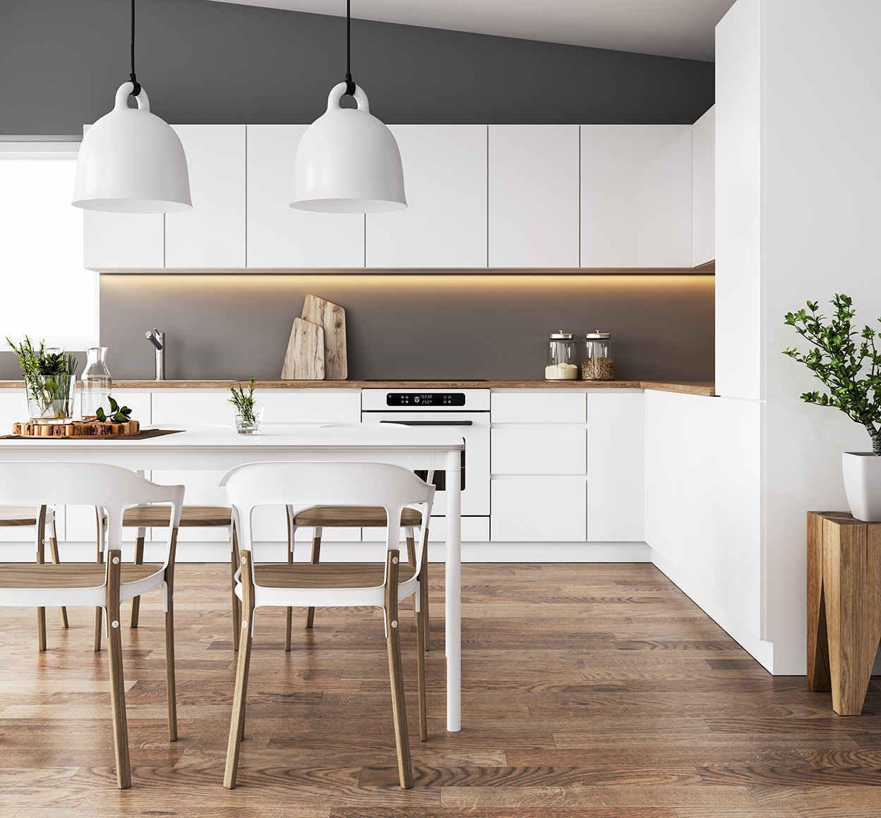 Une cuisine moderne en parquet, avec un comptoir avec un four, une table et des chaises