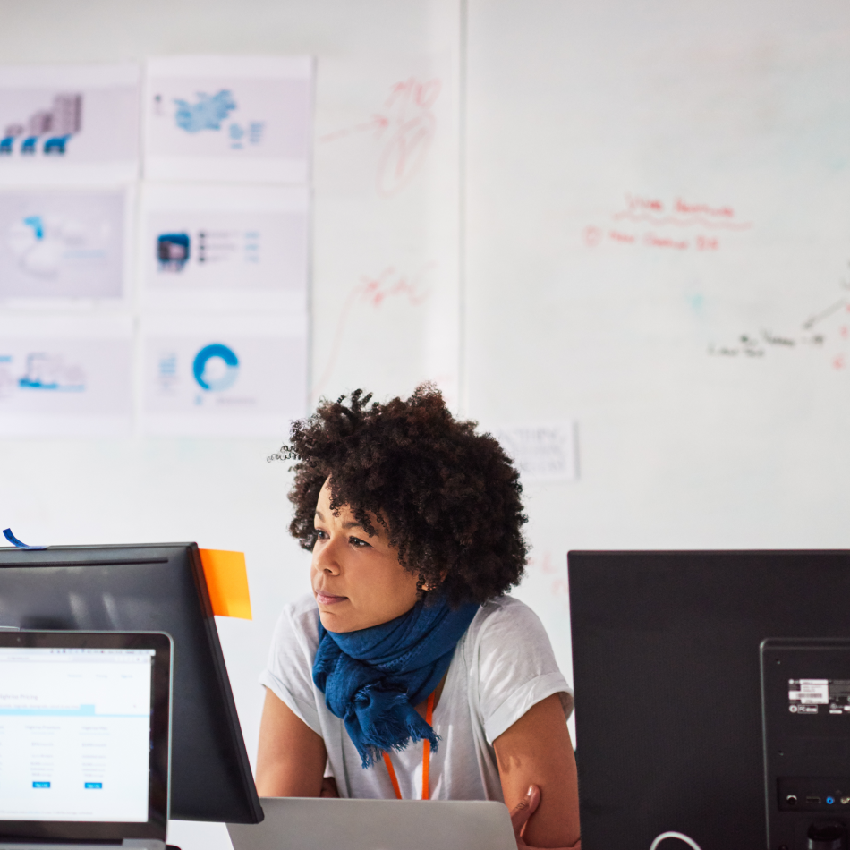 A focused businesswoman immersed in her work at a workstation in a modern tech start-up office.